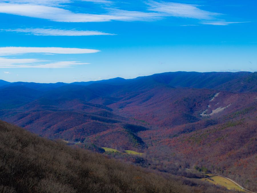 Rolling mountain ridges in autumn color stretching to the horizon under a blue sky.